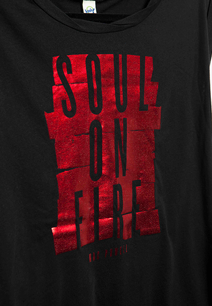 Close up of a black Mac Powell ladies t-shirt with a shiny red design that reads "Soul of Fire".