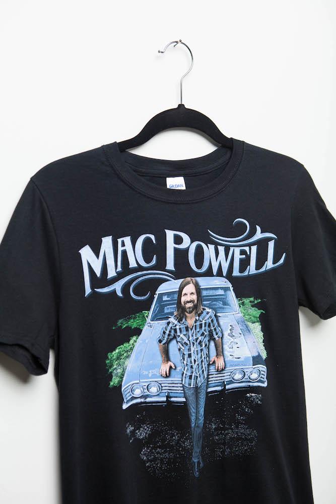 Close up of a black Mac Powell t-shirt that reads "Mac Powell" and has a photo of Mac leaning on a chevy car. 