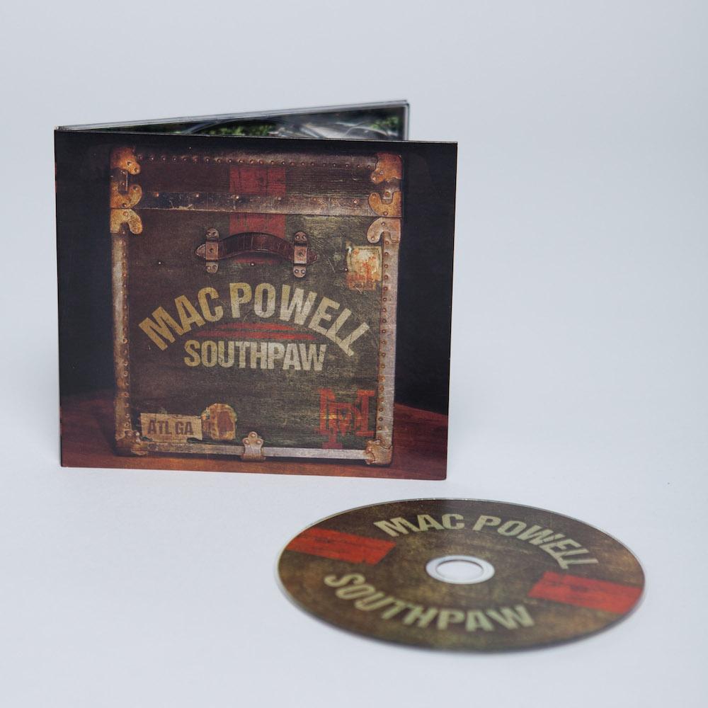 Mac Powell Southpaw CD that has a photo of a vintage chest on the cover displayed with the CD. 