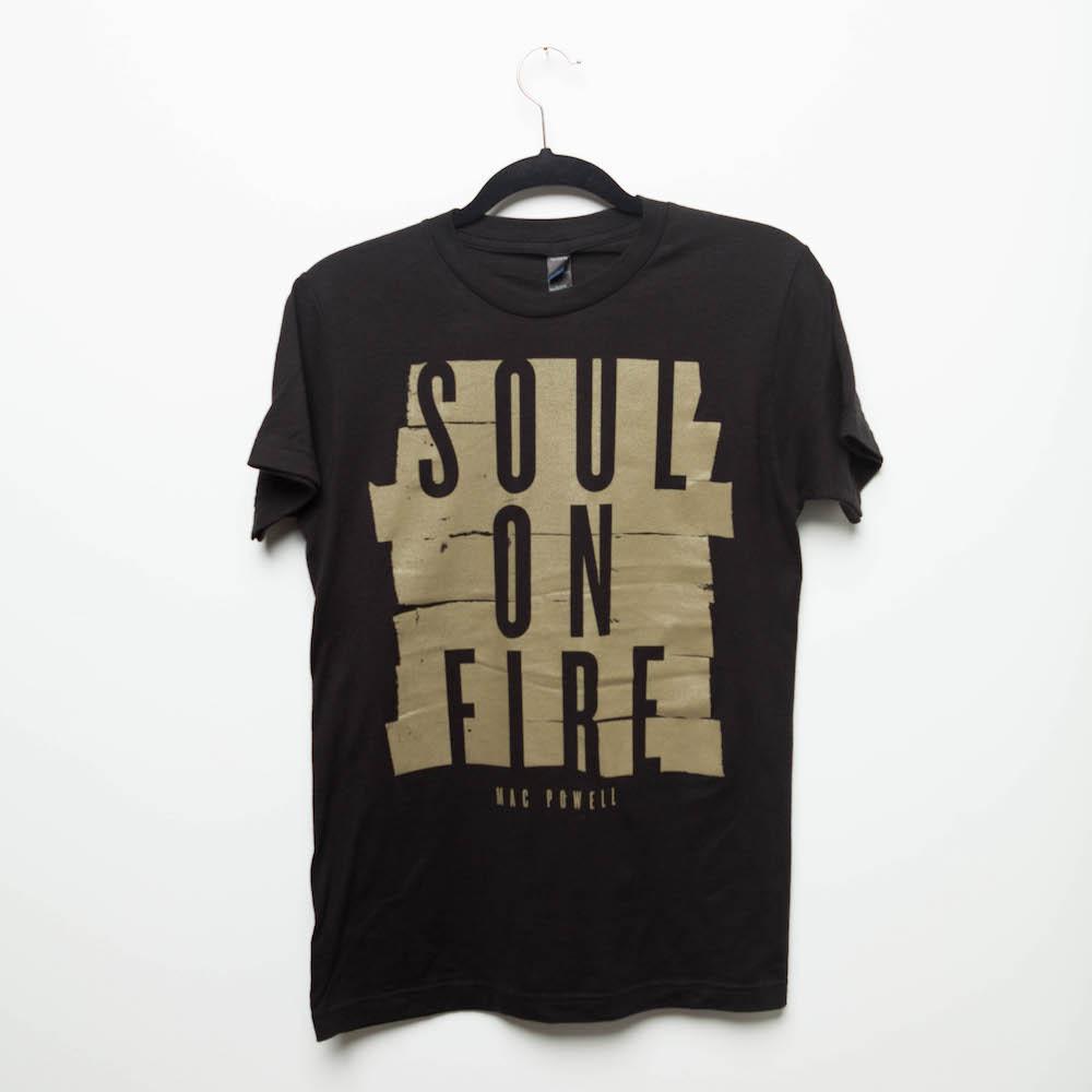 A black Mac Powell t-shirt with a gold design that reads "Soul of Fire".