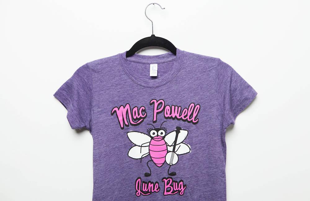 Close up of a purple ladies Mac Powell tee that reads "Mac Powell June Bug"
